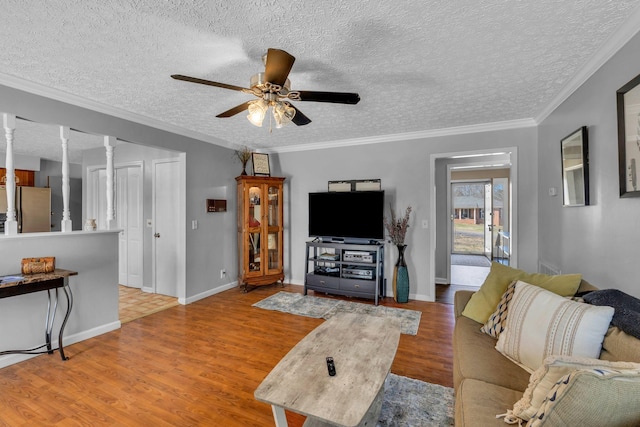 living room with wood finished floors, baseboards, ornamental molding, ceiling fan, and a textured ceiling