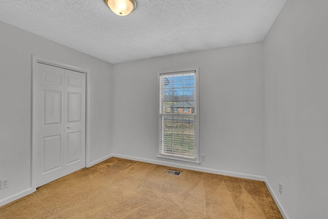 unfurnished room with baseboards, visible vents, carpet floors, and a textured ceiling