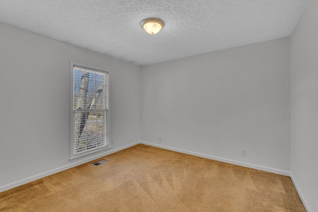 carpeted spare room featuring visible vents, a textured ceiling, and baseboards