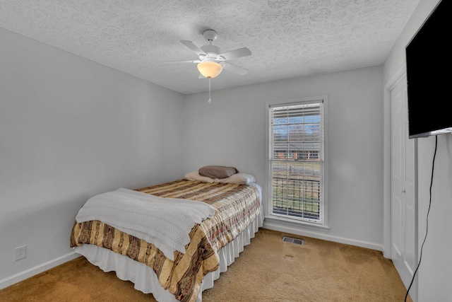 bedroom featuring visible vents, baseboards, light colored carpet, a closet, and a textured ceiling