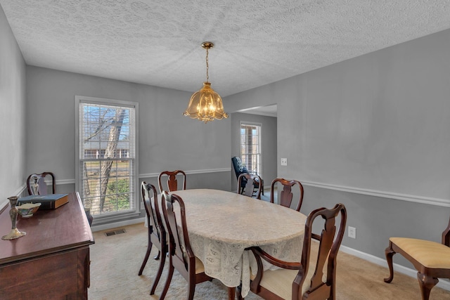 dining area with baseboards, visible vents, a textured ceiling, light carpet, and a chandelier