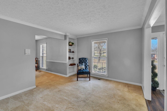 sitting room featuring carpet flooring, a textured ceiling, baseboards, and ornamental molding