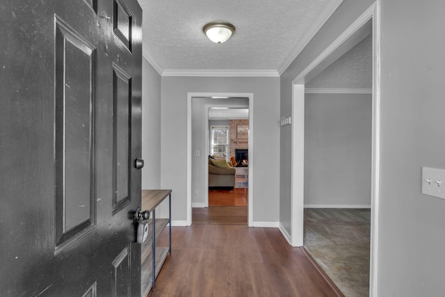 hall featuring wood finished floors, a textured ceiling, and ornamental molding