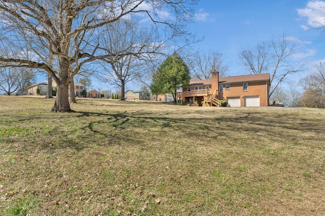 view of yard with a garage, a wooden deck, and stairs