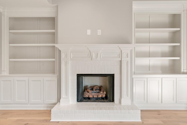 room details with built in shelves, a fireplace, and wood finished floors