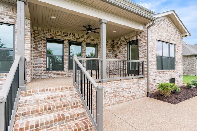 property entrance featuring brick siding, a ceiling fan, and covered porch