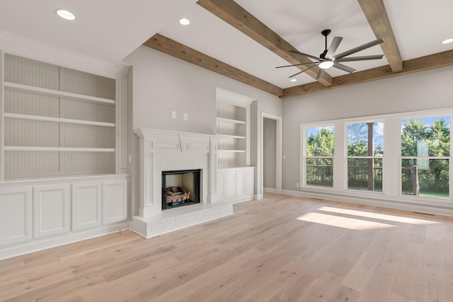 unfurnished living room featuring beamed ceiling, built in features, light wood-style flooring, and ceiling fan