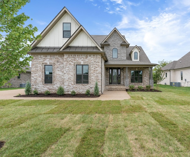 view of front facade with brick siding, board and batten siding, a front lawn, and a standing seam roof