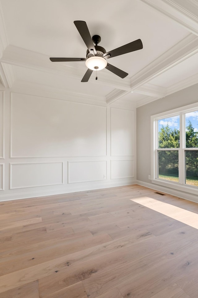 spare room with a decorative wall, visible vents, light wood finished floors, and ornamental molding