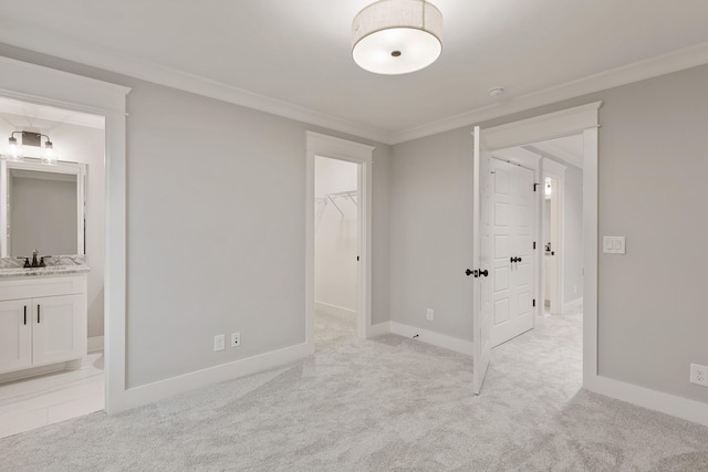 unfurnished bedroom with a walk in closet, crown molding, light colored carpet, and baseboards