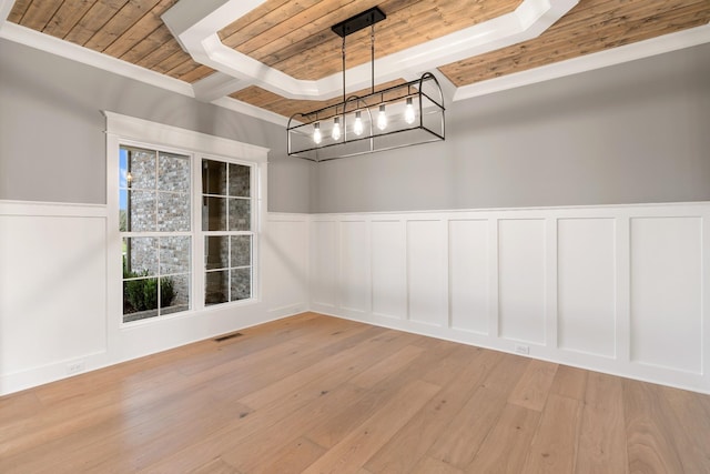 unfurnished dining area featuring visible vents, a tray ceiling, wood finished floors, a decorative wall, and wood ceiling