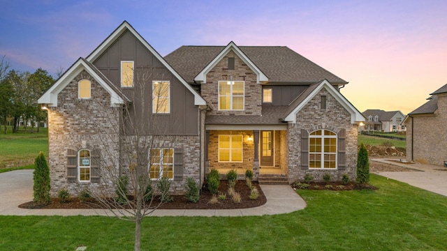 craftsman house with a lawn, board and batten siding, brick siding, and a shingled roof