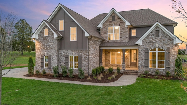 craftsman-style home with a lawn, board and batten siding, stone siding, and a shingled roof