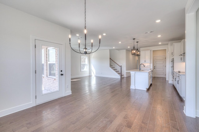 kitchen with a sink, a notable chandelier, an island with sink, and wood finished floors