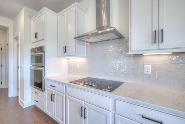 kitchen with dark wood finished floors, white cabinetry, double oven, wall chimney exhaust hood, and black electric cooktop