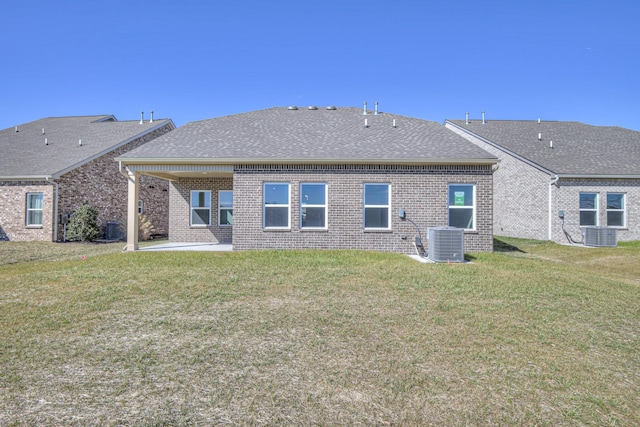 rear view of house featuring central air condition unit, brick siding, a lawn, and a patio area