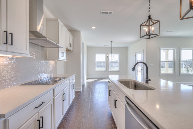 kitchen with a sink, dishwasher, wall chimney range hood, black electric cooktop, and a chandelier