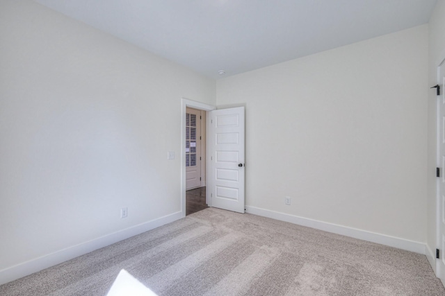 empty room with baseboards and light carpet