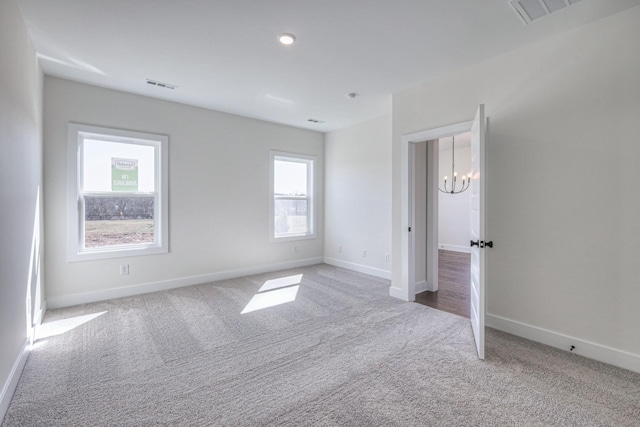 unfurnished bedroom featuring visible vents, carpet, and a notable chandelier