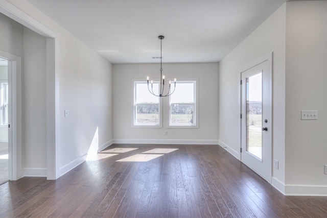 unfurnished dining area featuring baseboards, an inviting chandelier, and dark wood finished floors