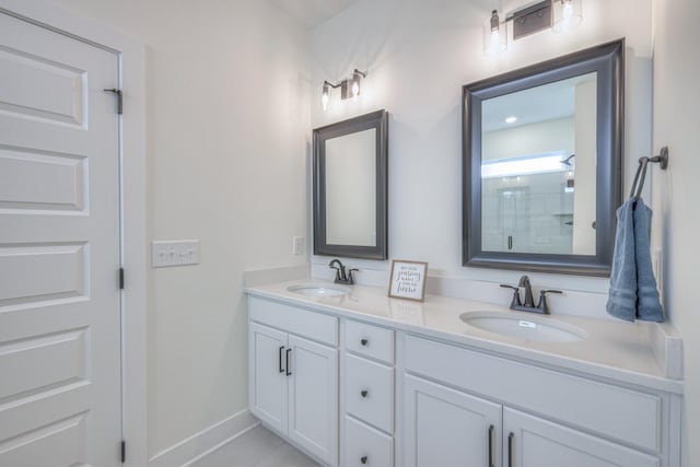 full bath with double vanity, a shower, baseboards, and a sink