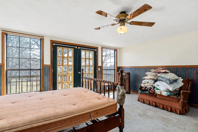 dining area with a wainscoted wall, a ceiling fan, a textured ceiling, french doors, and carpet