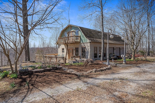 view of front of home featuring a gambrel roof and a balcony