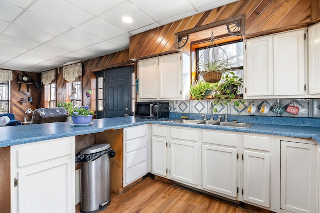 kitchen featuring wooden walls, a healthy amount of sunlight, a peninsula, and a sink