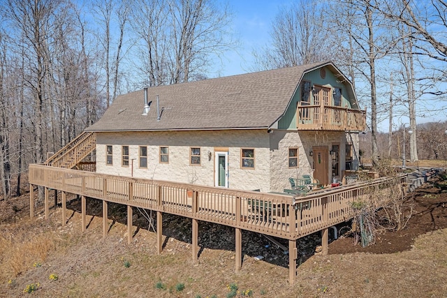 back of property featuring a balcony, a gambrel roof, a wooden deck, and roof with shingles