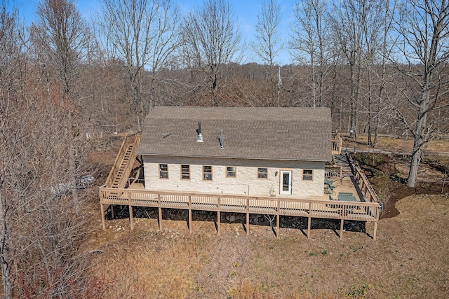 back of house featuring stairway, a deck, and roof with shingles