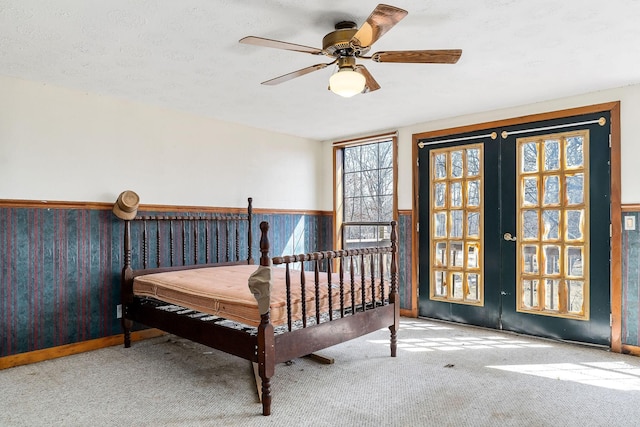 carpeted bedroom featuring french doors and a wainscoted wall