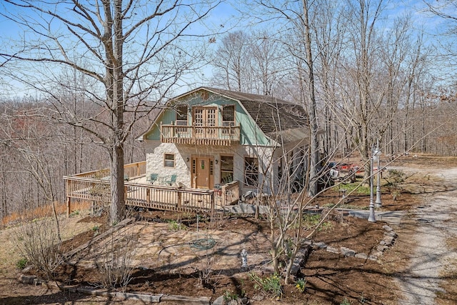 exterior space with a gambrel roof, a wooden deck, and a balcony