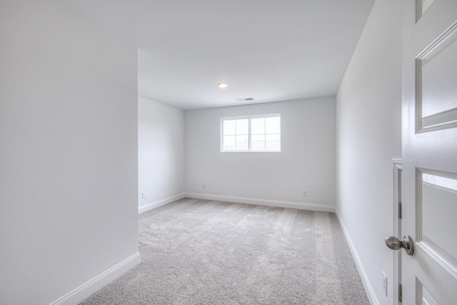 empty room featuring baseboards, visible vents, and light carpet