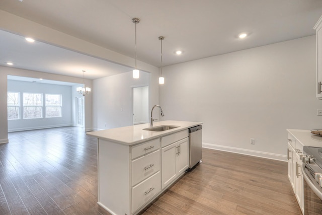 kitchen with light countertops, light wood-type flooring, an inviting chandelier, stainless steel appliances, and a sink