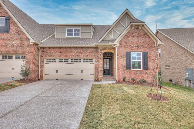 view of front facade with a front yard, driveway, roof with shingles, an attached garage, and brick siding