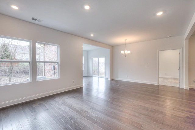 spare room featuring baseboards, visible vents, dark wood finished floors, recessed lighting, and a chandelier