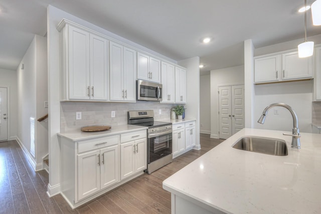 kitchen with a sink, wood finished floors, backsplash, and stainless steel appliances