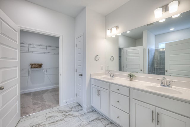 bathroom featuring double vanity, tiled shower, marble finish floor, and a sink