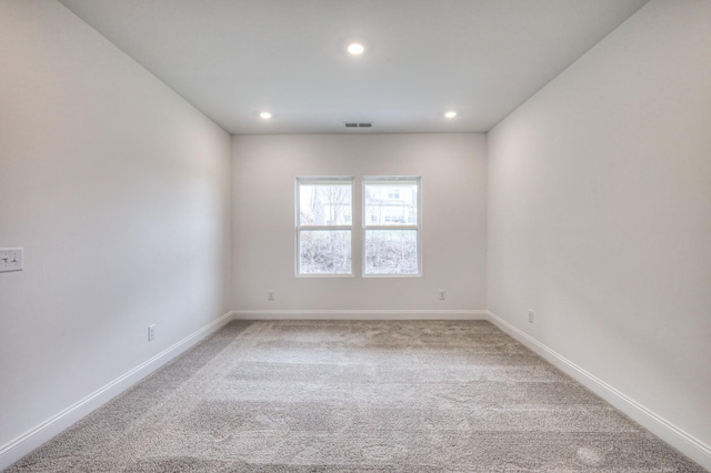 spare room with recessed lighting, baseboards, light carpet, and visible vents