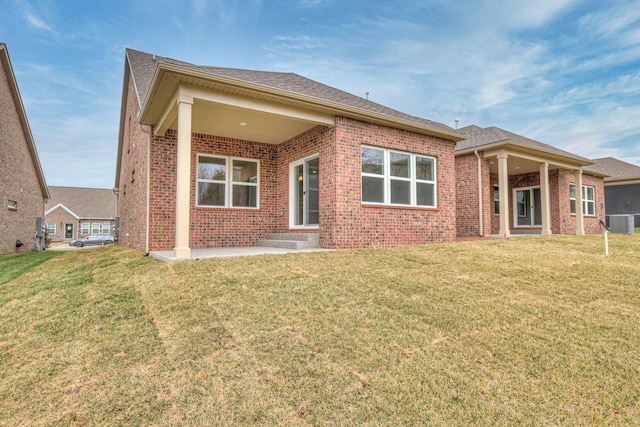 back of property with central air condition unit, a lawn, and brick siding