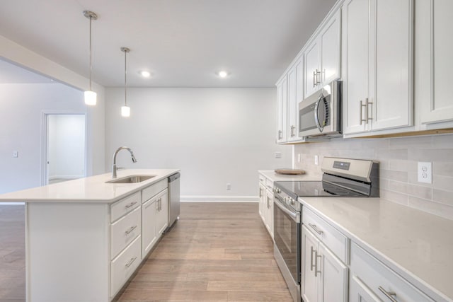 kitchen with backsplash, light countertops, light wood-style flooring, stainless steel appliances, and a sink