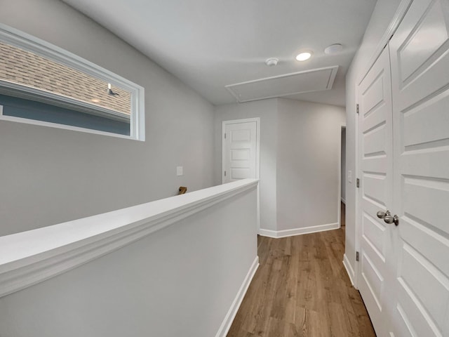 hall featuring baseboards, attic access, and wood finished floors