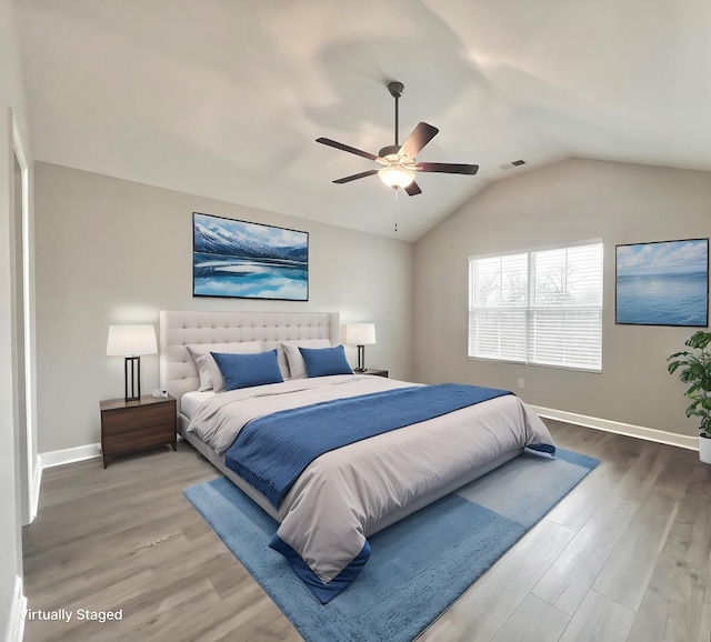 bedroom with lofted ceiling, wood finished floors, visible vents, and baseboards