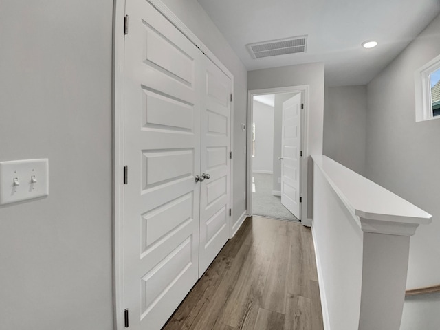 hallway featuring visible vents, recessed lighting, baseboards, and wood finished floors