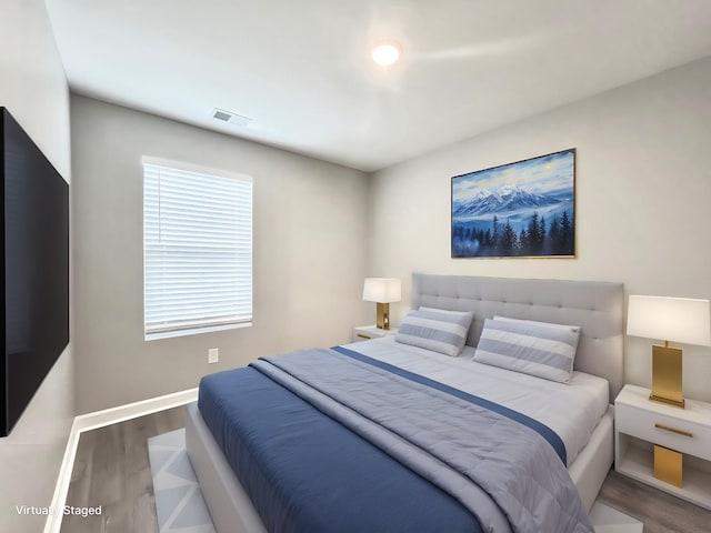 bedroom with wood finished floors, visible vents, and baseboards