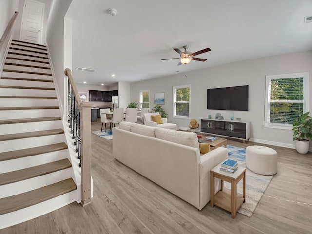 living room with light wood-type flooring, a ceiling fan, recessed lighting, stairway, and baseboards