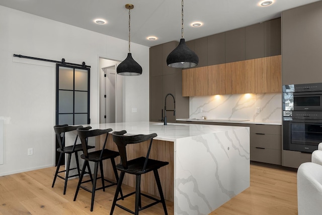 kitchen with a barn door, modern cabinets, dobule oven black, and a sink