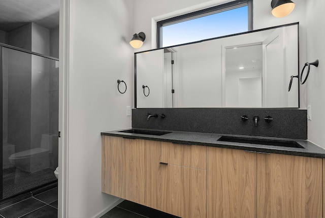 full bathroom featuring tile patterned flooring, a shower stall, toilet, and a sink