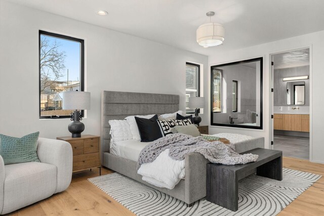 bedroom with a sink, recessed lighting, ensuite bath, and wood finished floors