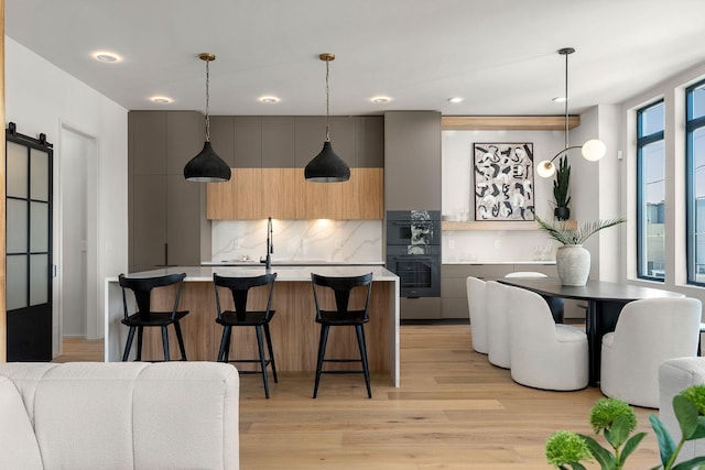 kitchen with light countertops, decorative backsplash, light wood-style flooring, modern cabinets, and dobule oven black